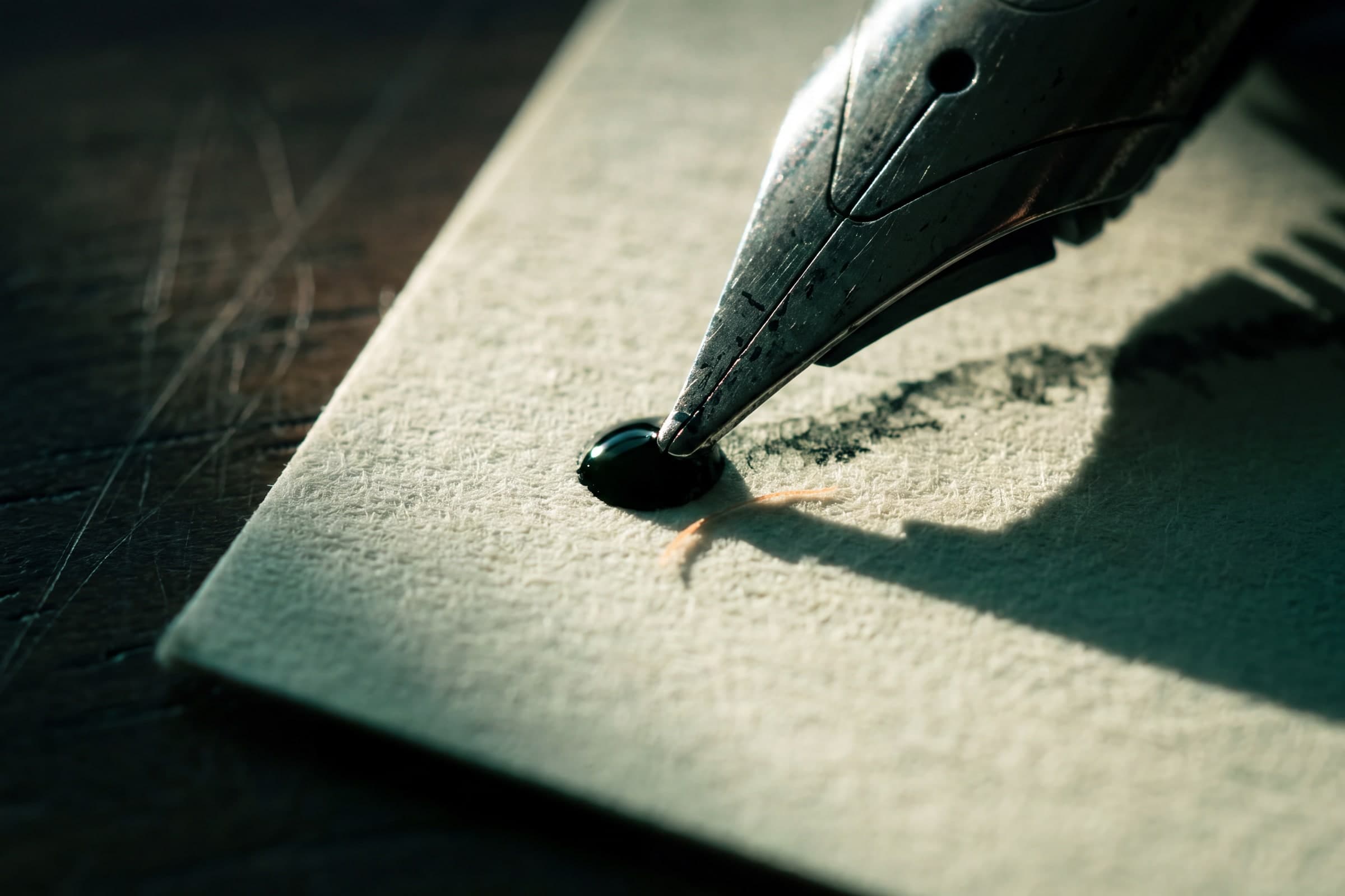 A fountain pen nib resting on paper, the ink still wet.